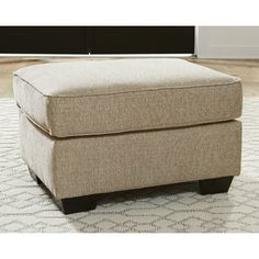 a beige ottoman sitting on top of a rug