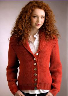 a woman wearing a red cardigan sweater and black pants with her hands in her pockets