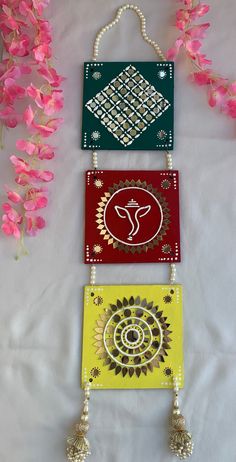 three colorful cards with designs on them and some beads hanging from the strings next to pink flowers