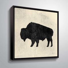 a black and white buffalo silhouette mounted on a wall above a gray background with the word,