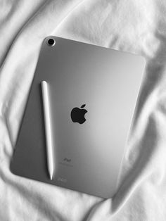 an apple ipad on top of a white sheet with a pen sticking out of it