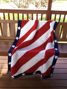 a red, white and blue blanket sitting on top of a wooden bench