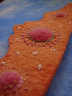 an orange piece of fabric with small pink flowers on it, sitting on top of a blue table cloth