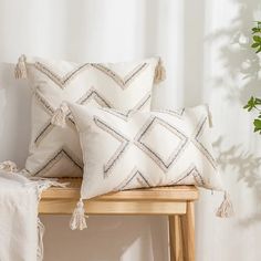 two white pillows on a wooden bench next to a potted plant