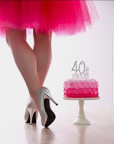 a woman in high heels standing next to a pink cake with the number 40 on it