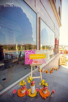 flowers are placed on the sidewalk in front of a storefront with an easel