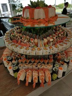 an assortment of sushi and sashimi displayed on three tiered platter