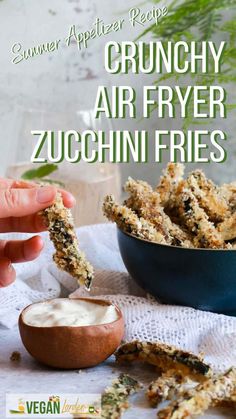 a person dipping some food into a bowl with ranch dressing in it and the words crunchy air fryer zucchini fries