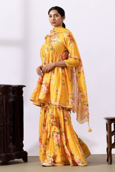 Mustard yellow gathered kurta with floral digital prints and lace detailing. Paired with printed gharara and dupatta.
Components: 3
Pattern: Printed
Type Of Work: Floral
Neckline: V neck
Sleeve Type: Three quarter
Fabric: Chanderi
Color: Yellow
Other Details: 
Lace detailing
Tassel tie-up
Tassel detailing on edge of dupatta
Scallop border
Occasion: Puja - Aza Fashions Unstitched Yellow Traditional Wear With Meenakari, Yellow Sharara For Wedding And Eid, Yellow Semi-stitched Sharara For Designer Wear, Yellow Semi-stitched Traditional Wear With Dabka, Designer Yellow Lehenga With Dabka Detail, Designer Yellow Lehenga With Dabka Embroidery, Semi-stitched Yellow Palazzo Set For Wedding, Designer Yellow Dupatta With Dabka, Semi-stitched Yellow Sets With Sheer Dupatta