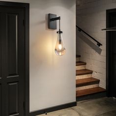 a light that is on the side of a wall next to a door and stairs