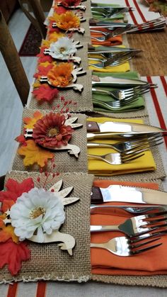 the table is set with silverware and flowers on burlap runneres, along with orange napkins