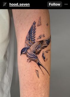 a blue bird flying through the air with an arrow in its beak and triangles around it