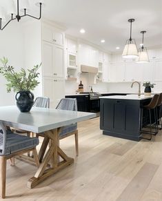 a kitchen and dining room with white cabinets, wood flooring and an island in the middle