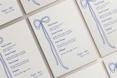 wedding stationery cards with blue ink on white paper, tied with ribbon and bow