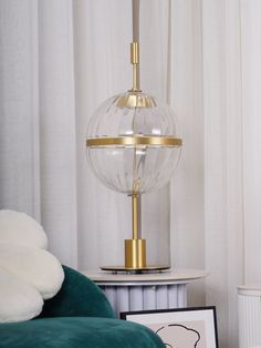 a glass lamp sitting on top of a table next to a bed with white sheets