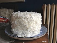 a large white cake sitting on top of a plate next to a stack of books