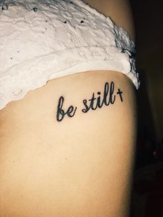 a woman's stomach with the words be still tattooed on her lower side belly