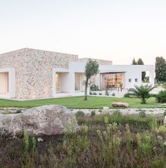 a large rock in front of a house with grass and rocks on the ground next to it