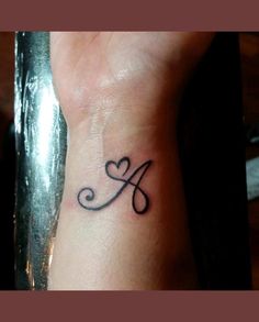 a small tattoo on the wrist of a woman's left hand with a heart