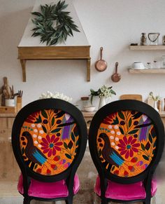 two chairs with designs on them sit in front of a fireplace