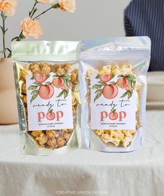 two bags of popcorn sitting on top of a table next to a vase with flowers