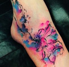 a watercolor tattoo on the leg of a woman with flowers painted all over it