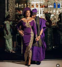 a man and woman dressed in traditional african garb walking down the runway at a fashion show