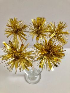 four gold foiled flowers in a clear glass vase