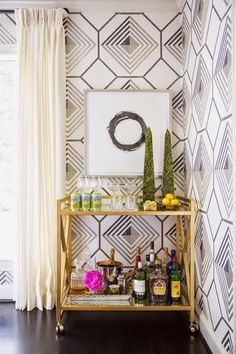 a shelf with bottles and other items on it in front of a wallpapered room