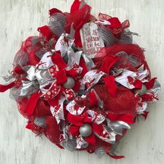 a red and silver christmas wreath on a white wooden surface