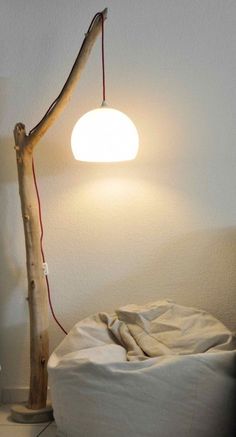 a lamp that is sitting on top of a wooden pole next to a white bed