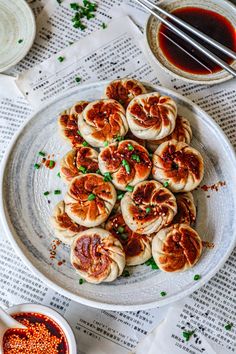 some food is sitting on a plate with chopsticks and sauce in the bowl