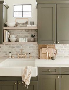 a kitchen with gray cabinets and white counter tops, an open shelving above the sink