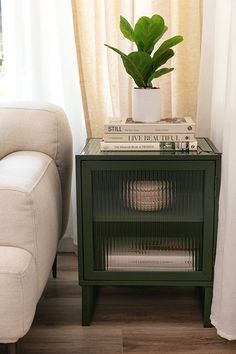 a green side table with books and a potted plant sitting on top of it