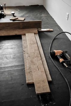 some tools are laying on the floor next to a piece of wood