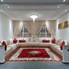 a living room filled with white couches and red rugs on top of a hard wood floor