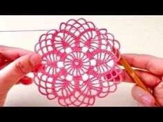 two hands crocheting a pink doily