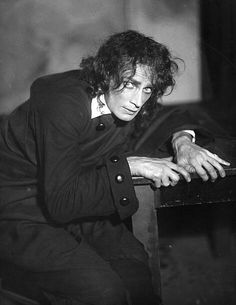 black and white photograph of a man leaning on a table with his hand resting on the edge