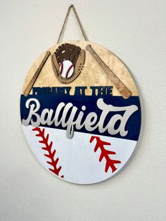 a sign hanging on the side of a wall with baseballs and bats painted on it