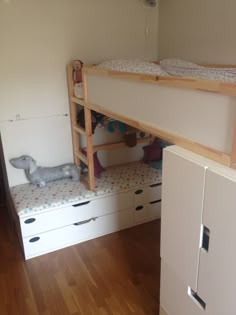 a bunk bed sitting in the corner of a room next to a white freezer