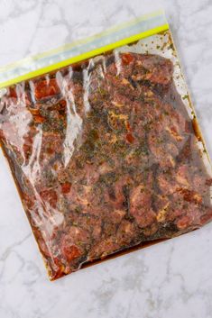 a bag filled with meat sitting on top of a white marble countertop next to a knife