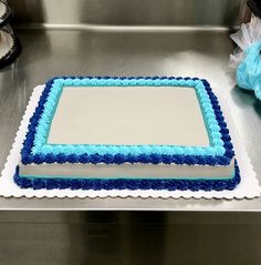 a blue and white cake sitting on top of a metal counter next to a bag