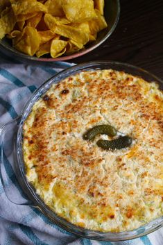 a baked dish with tortilla chips and salsa in the bowl next to it