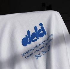 the back of a white shirt with blue logos on it