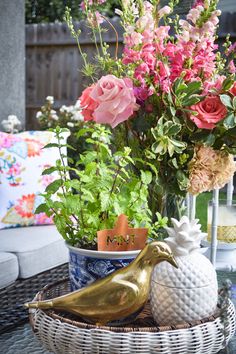 a basket filled with flowers sitting on top of a table next to a bird figurine