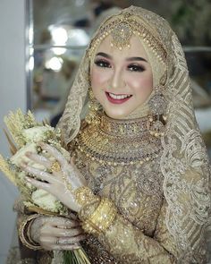 a woman in a wedding dress holding flowers and smiling at the camera while wearing a veil