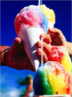 a person holding an ice cream sundae in front of a blue sky and ocean