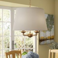 a chandelier hanging over a dining room table with blue hydrangeas on it