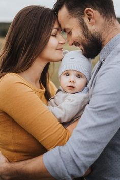 a man and woman holding a baby in their arms