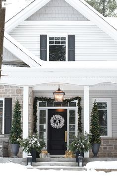 a white house with black shutters and a wreath on the front door in winter